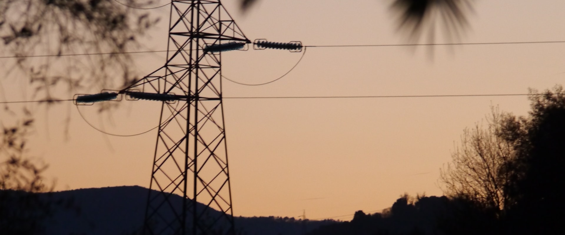 Power lines running through open countryside at dusk.